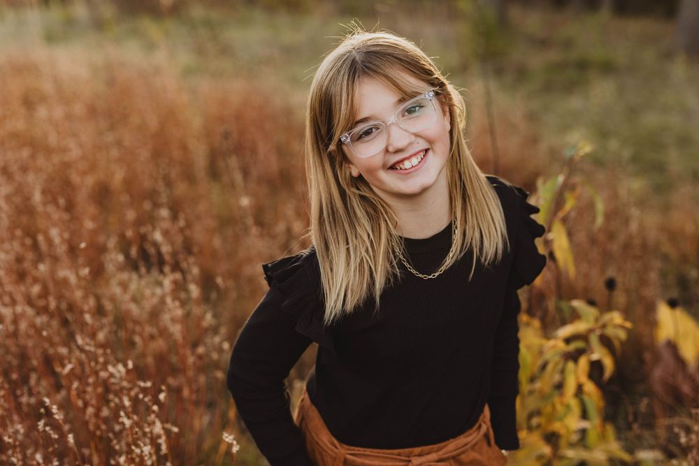 Candid outdoor family portraits in fall field with natural lighting.