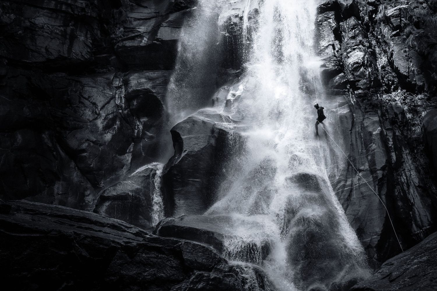 Dramatic black and white waterfall sequence showing climbers ascending ice formations.