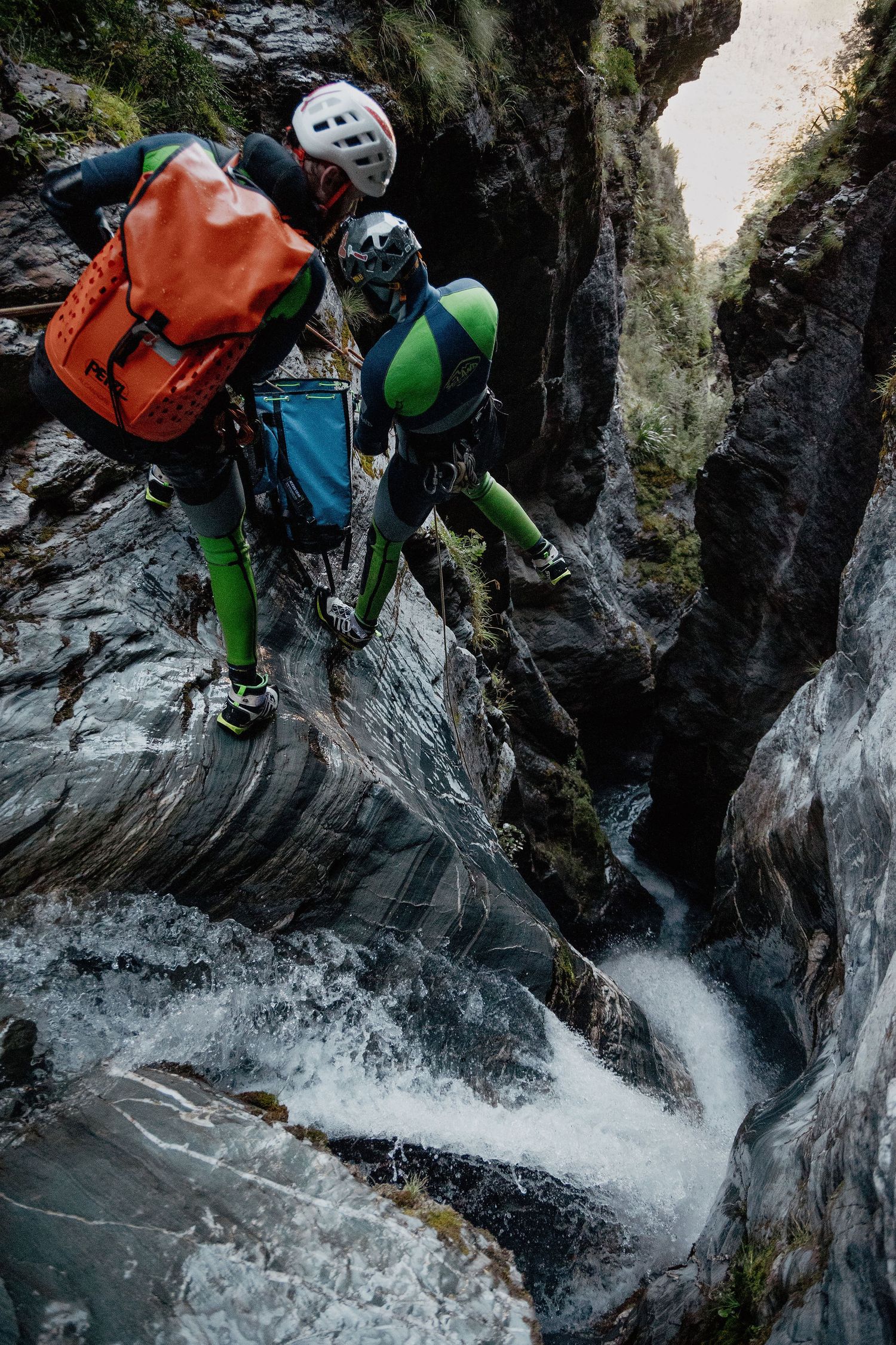 Two canyoneers dangle above a slot canyon in New Zealand