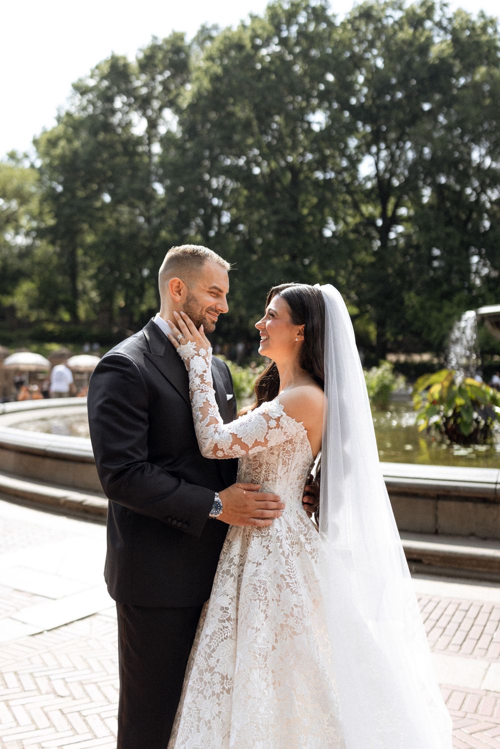 A couple shares a joyful moment during their wedding photoshoot in a park setting.