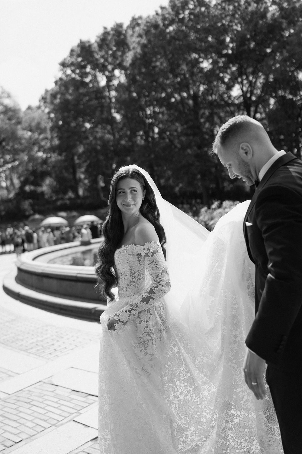 A couple in wedding attire poses together on a brick pathway during their photoshoot.