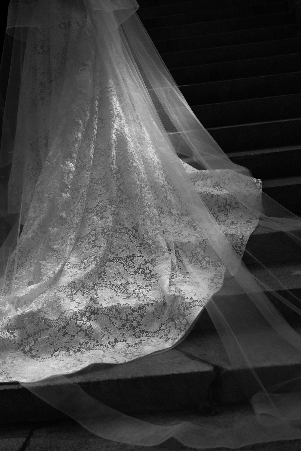 Close-up detail of an intricate lace wedding dress train with delicate embroidery patterns.