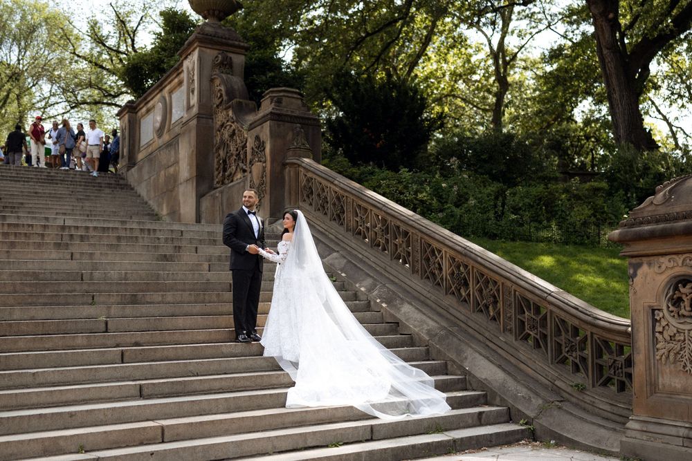 A couple ascends stone steps during their wedding photoshoot in a park setting.