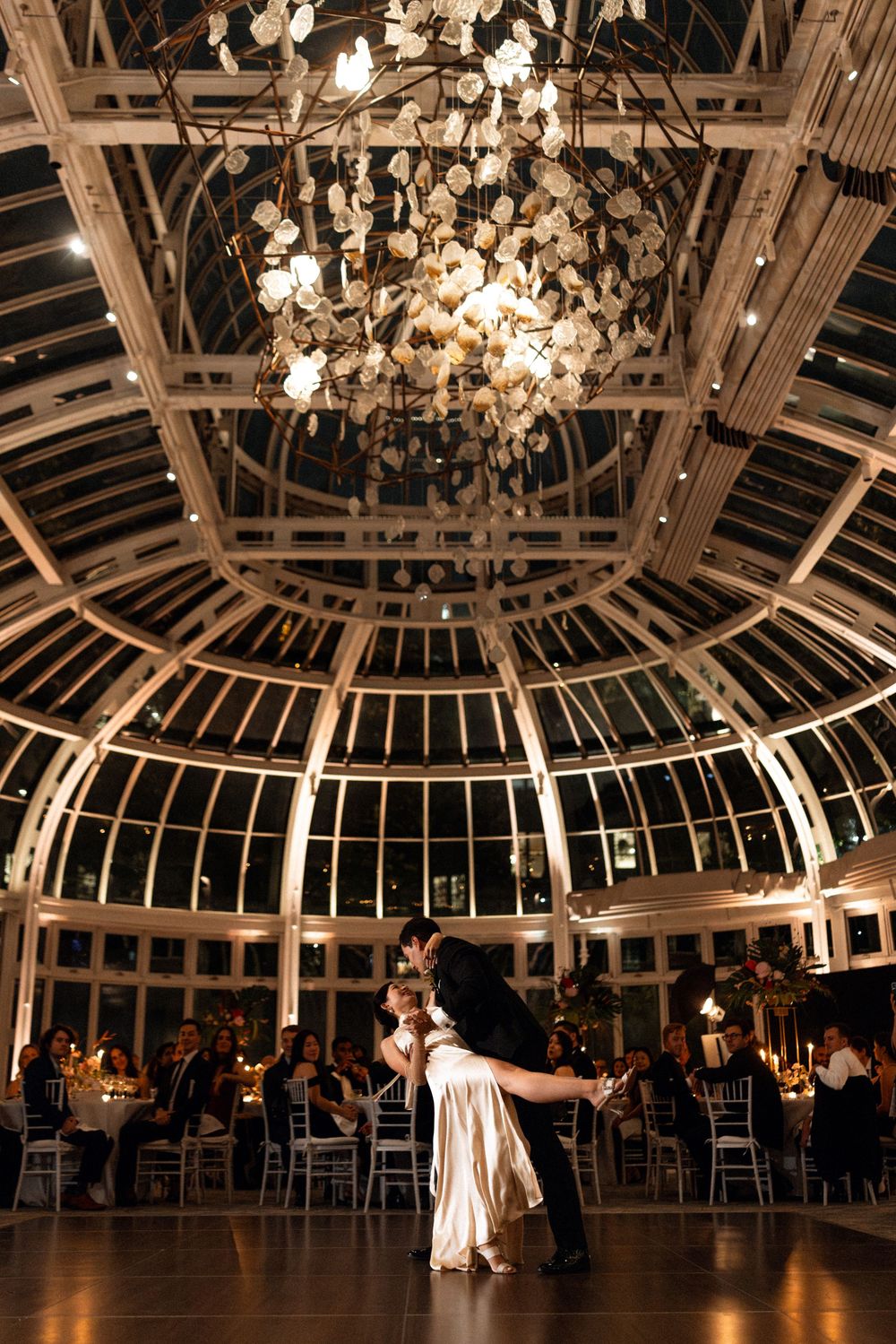 Elegant wedding reception venue with ornate domed glass ceiling and crystal chandeliers illuminating the dance floor.