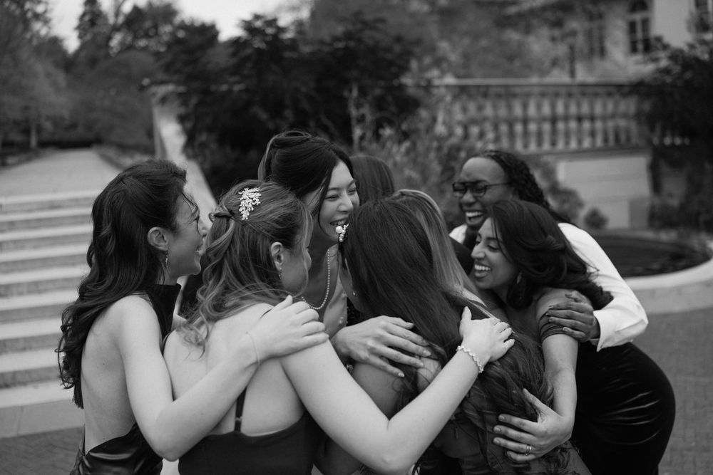 Group of wedding guests embracing in a heartfelt moment captured in black and white.