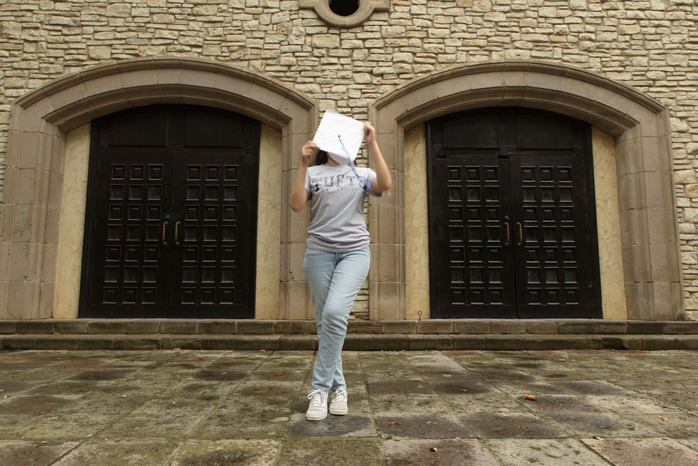 high school senior using graduation cap to cover face
