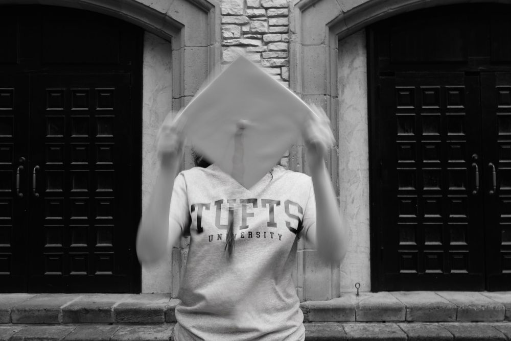 high school senior using graduation cap to cover face and show movement for still photo