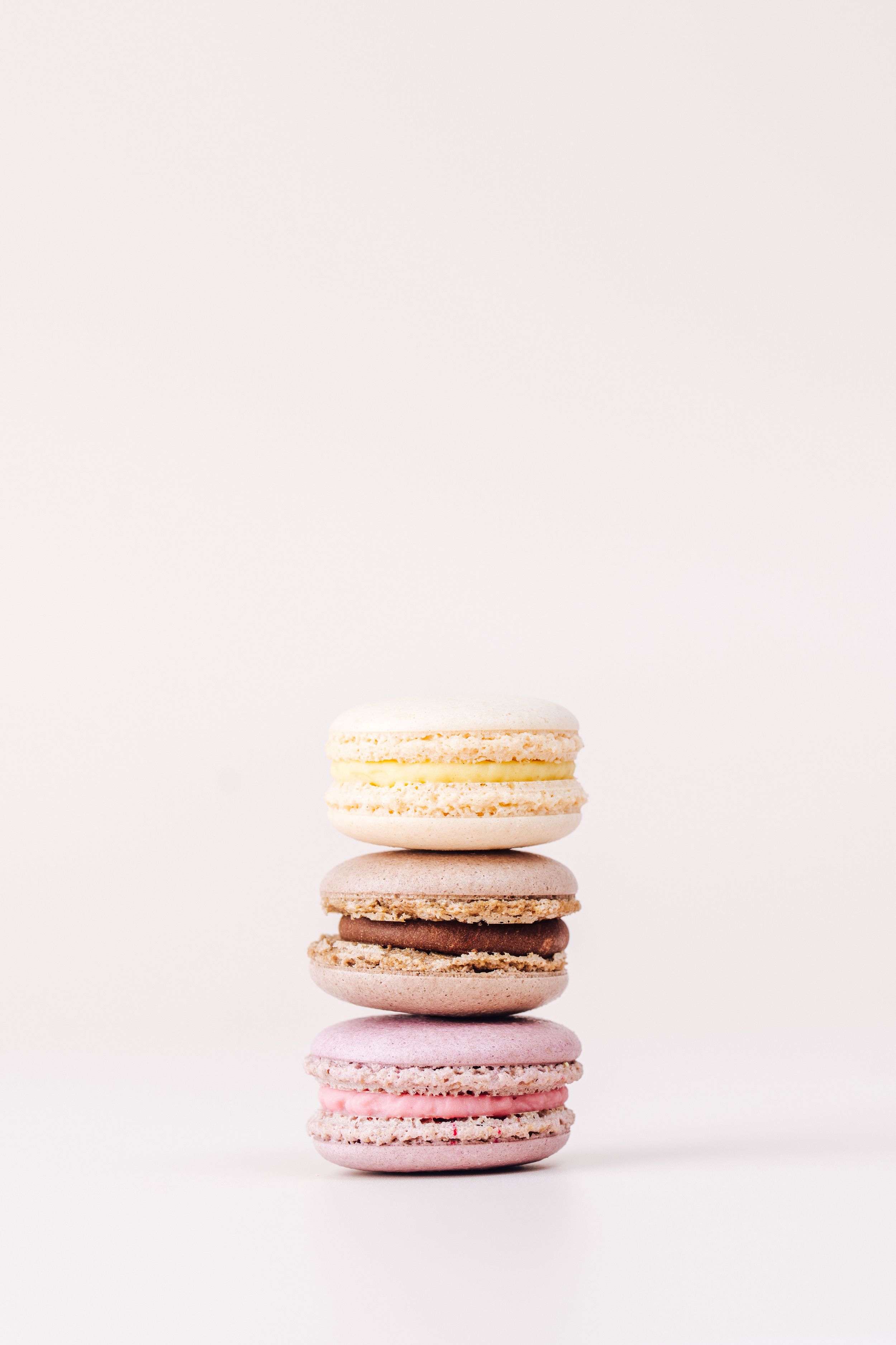Pastel colored macarons stacked delicately against white background.