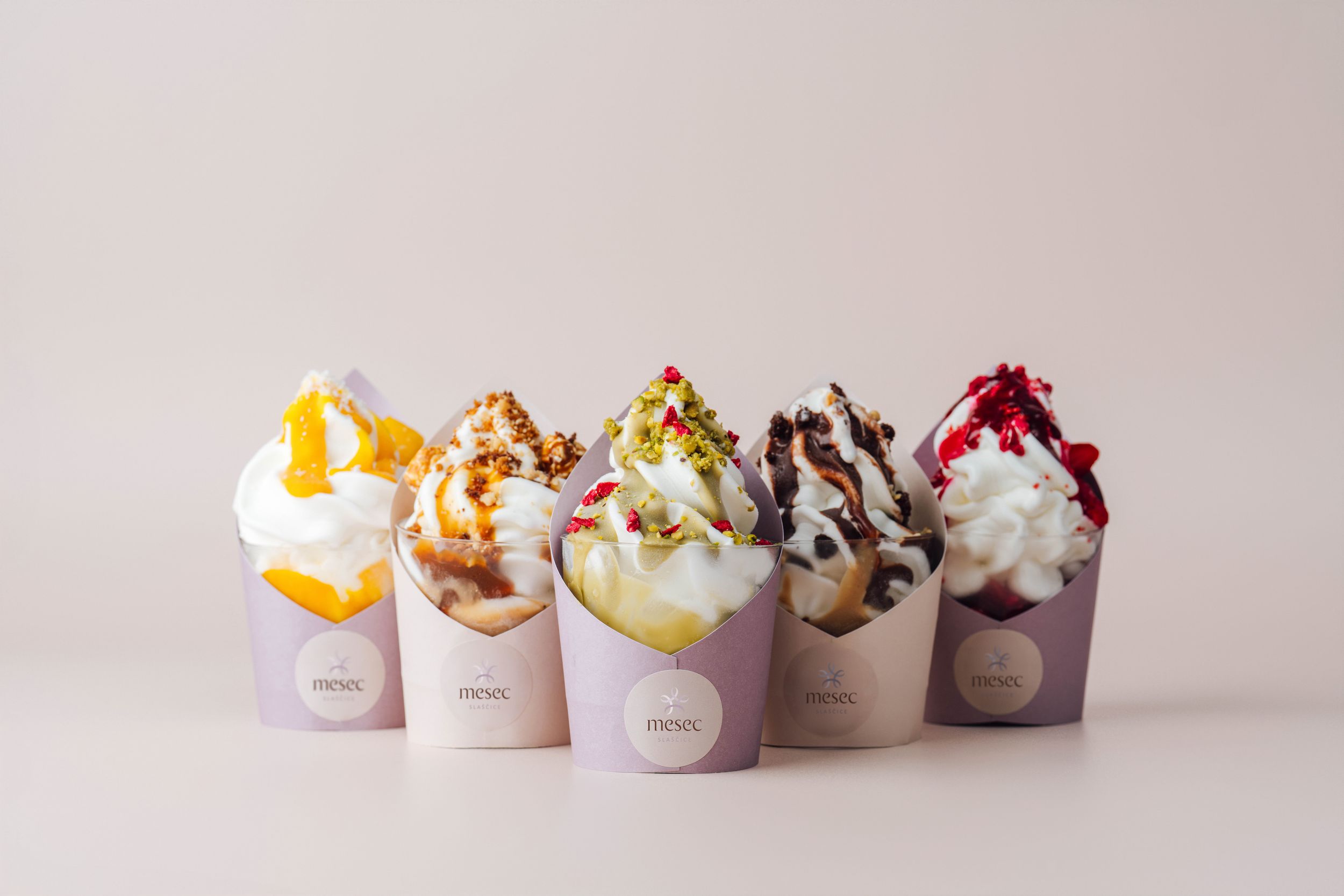 Row of artisanal ice cream desserts in purple wrappers displayed on white background.