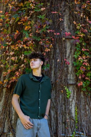 A dark green button-up shirt stands against a wall covered in colorful autumn ivy vines.