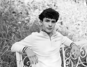 A black and white photo series showing someone sitting on an ornate white metal bench in a garden setting.
