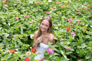 A joyful moment captured in a lush garden filled with vibrant pink and red zinnias on a sunny day.