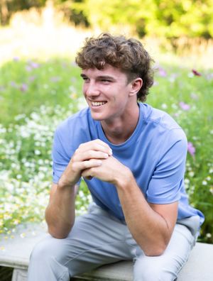 A person wearing a blue t-shirt sits outdoors smiling and laughing in a series of candid portrait shots.