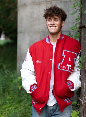 A red and white varsity letterman jacket styled in multiple similar poses against a natural outdoor background.