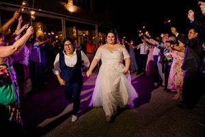 Wedding celebration with dancing and guests on a dance floor illuminated by purple lights at a night reception.