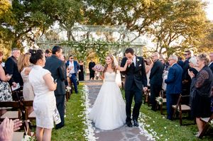 A romantic outdoor wedding ceremony in a garden with guests sitting on white chairs during golden hour.