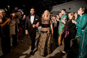 Wedding guests in formal attire dancing and celebrating on a dimly lit dance floor at a reception celebration.