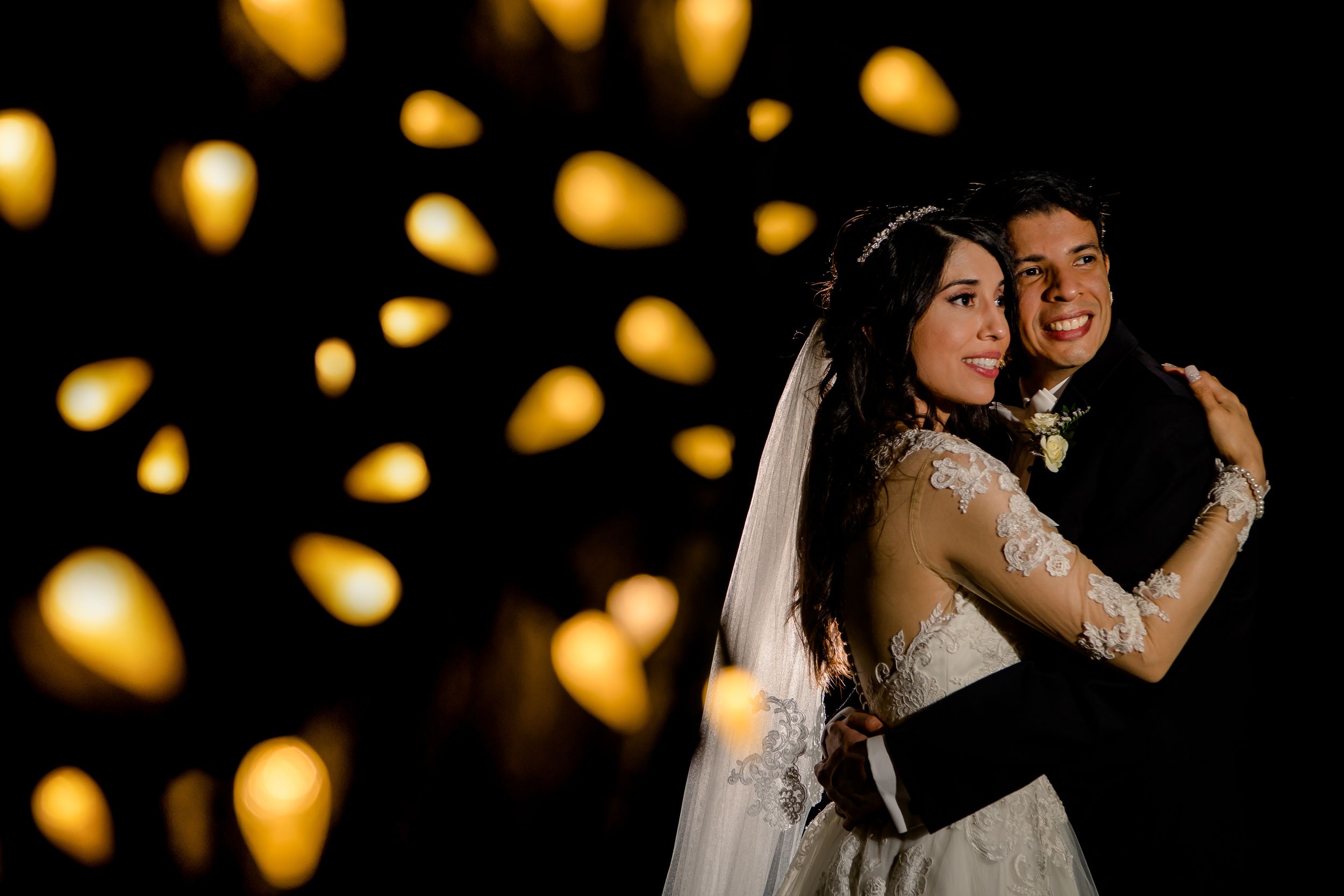 Romantic first dance at wedding reception with bokeh lights in the background creating dreamy atmosphere.
