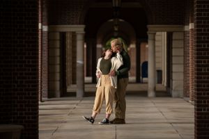 Two figures dancing together in an elegant covered walkway with brick columns.