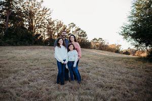 Family sitting together on a grassy hillside during golden hour sunset.