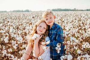 Casual family portrait session among rows of cotton plants on a sunny day.