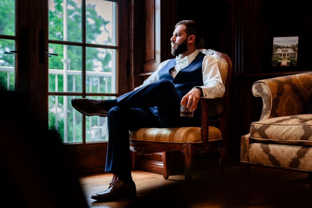 Moody indoor portrait with natural window lighting in elegant room setting.