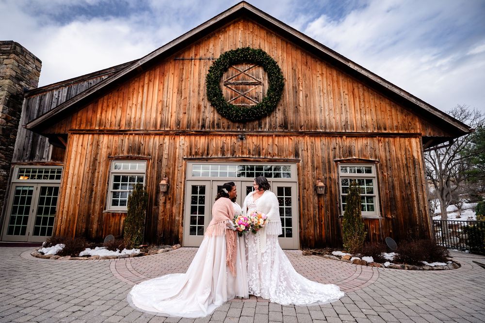A rustic wooden barn venue with weathered siding serves as a backdrop for an elegant wedding celebration.