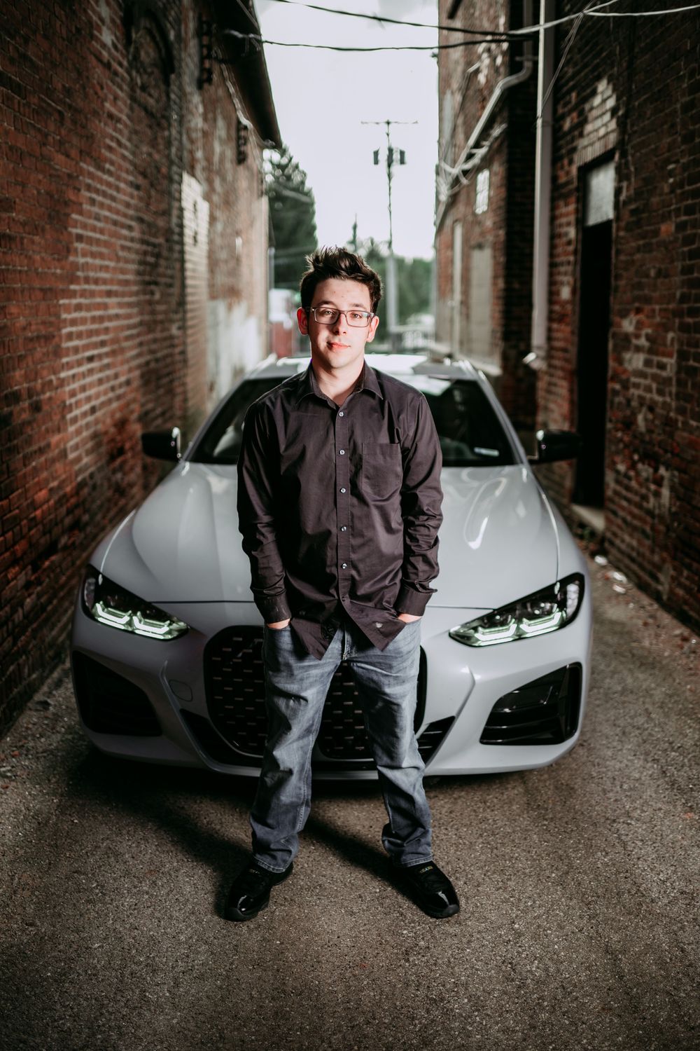 Urban photoshoot in alley with white car and brick walls.