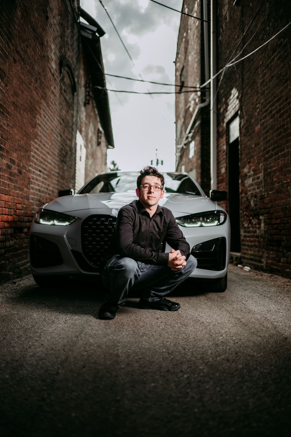 Creative low angle portrait with luxury car in brick alleyway.