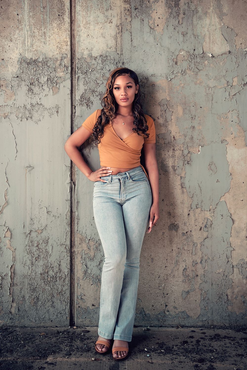 Portrait series against weathered concrete wall showing casual style.