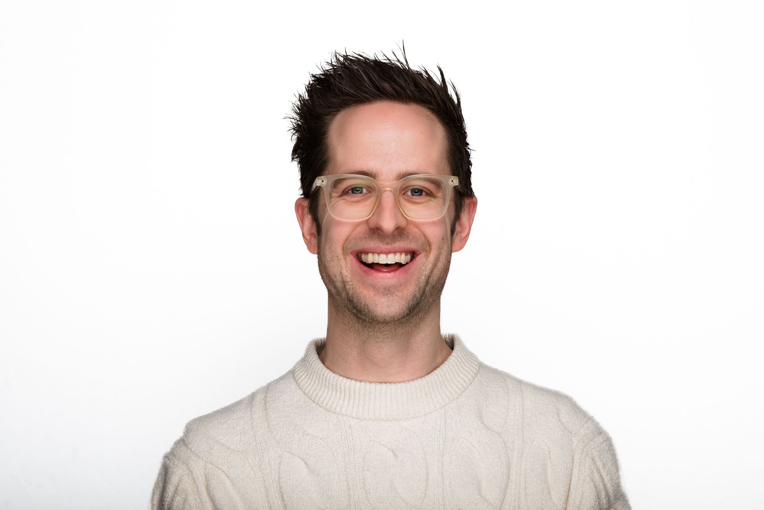 A portrait of someone wearing a white sweater smiling warmly against a white background.