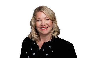 Professional headshot of someone wearing a black polka dot blouse against a white background.