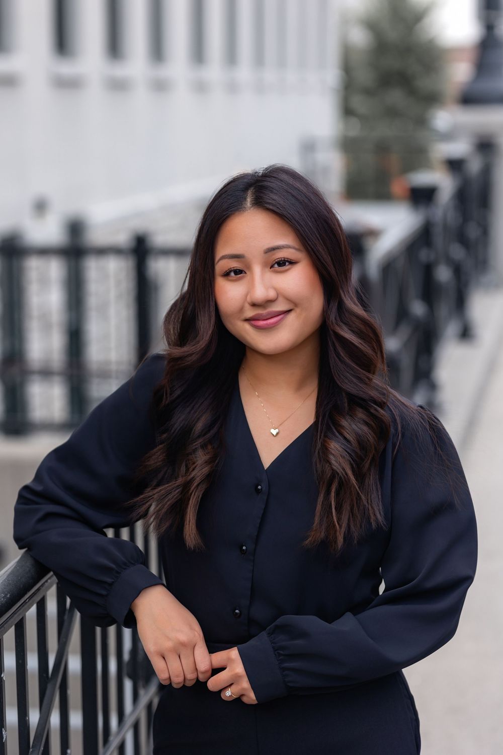 Professional headshots of a person in a black blazer posing against an urban background.