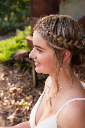 Close-up profile view showcasing intricate braided hairstyle and delicate jewelry.