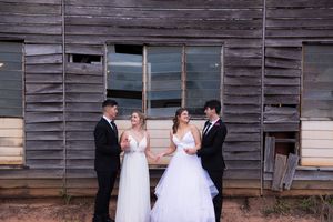 Wedding couple poses in front of rustic wooden building wall for portrait series.