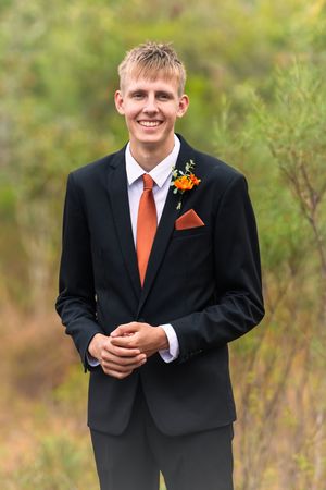 A formal portrait series showing someone in a black suit with orange tie and boutonniere.