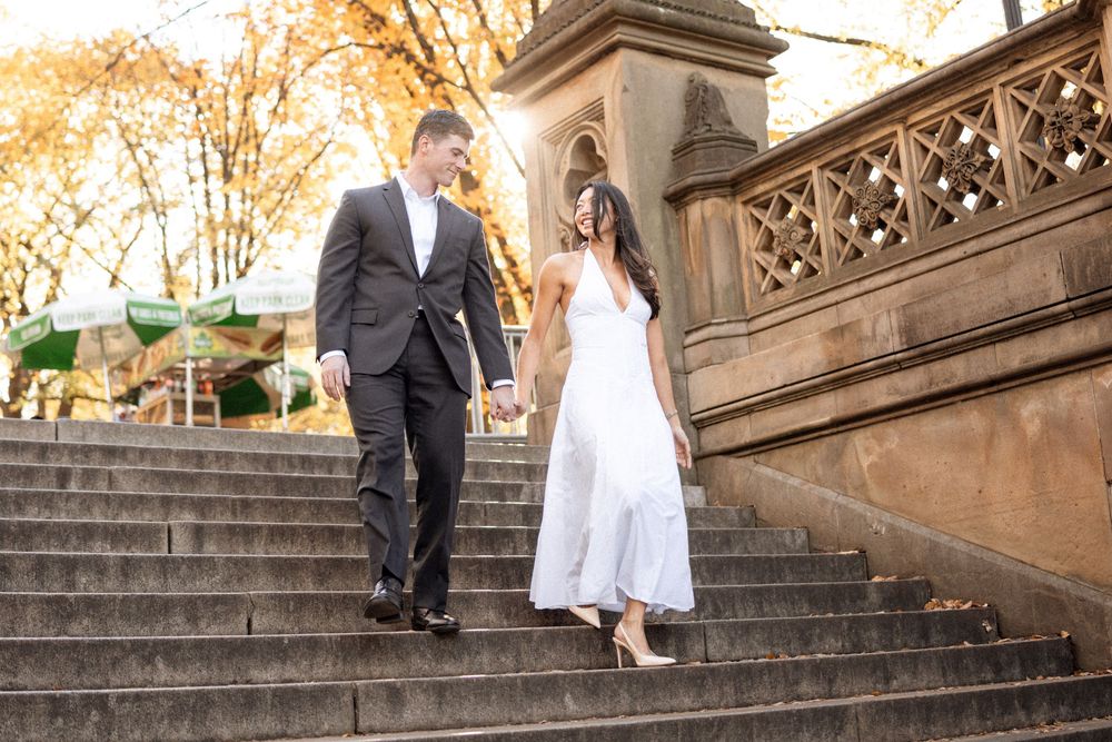 Wedding party walking up grand stone steps during golden hour.