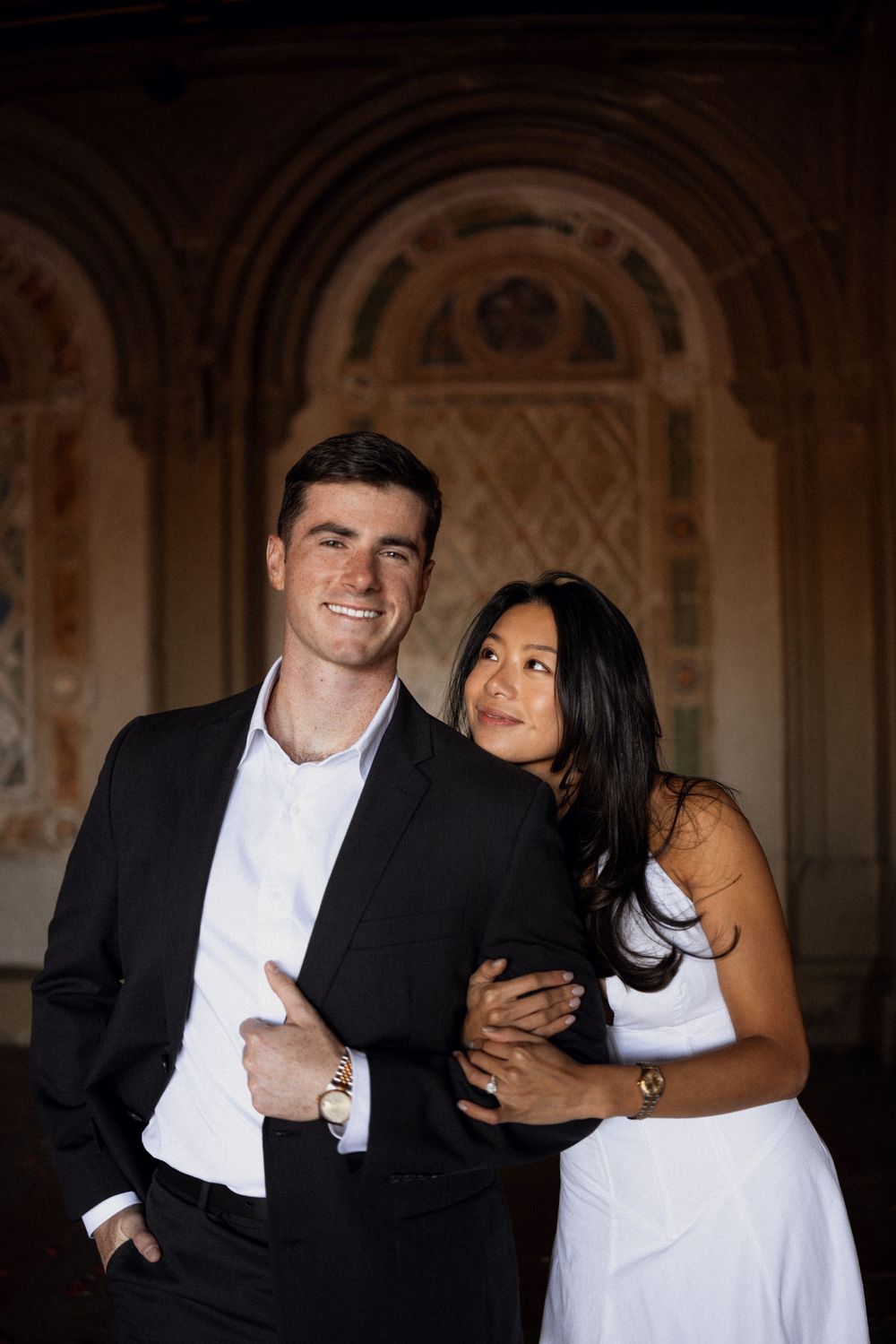 Joyful couple sharing intimate moments in an elegant architectural setting.