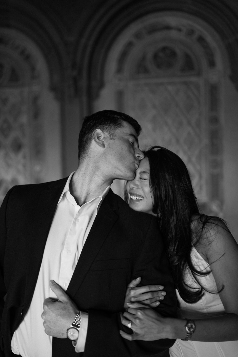 Candid black and white photos capturing romantic moments in a historic hallway.