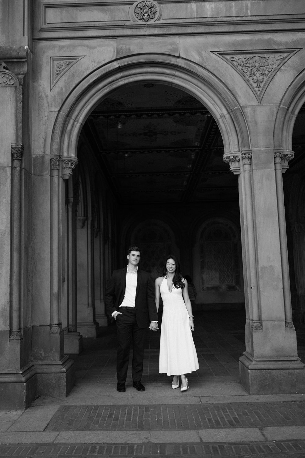 Wedding couple photographed in dramatic silhouette under historic stone archways.
