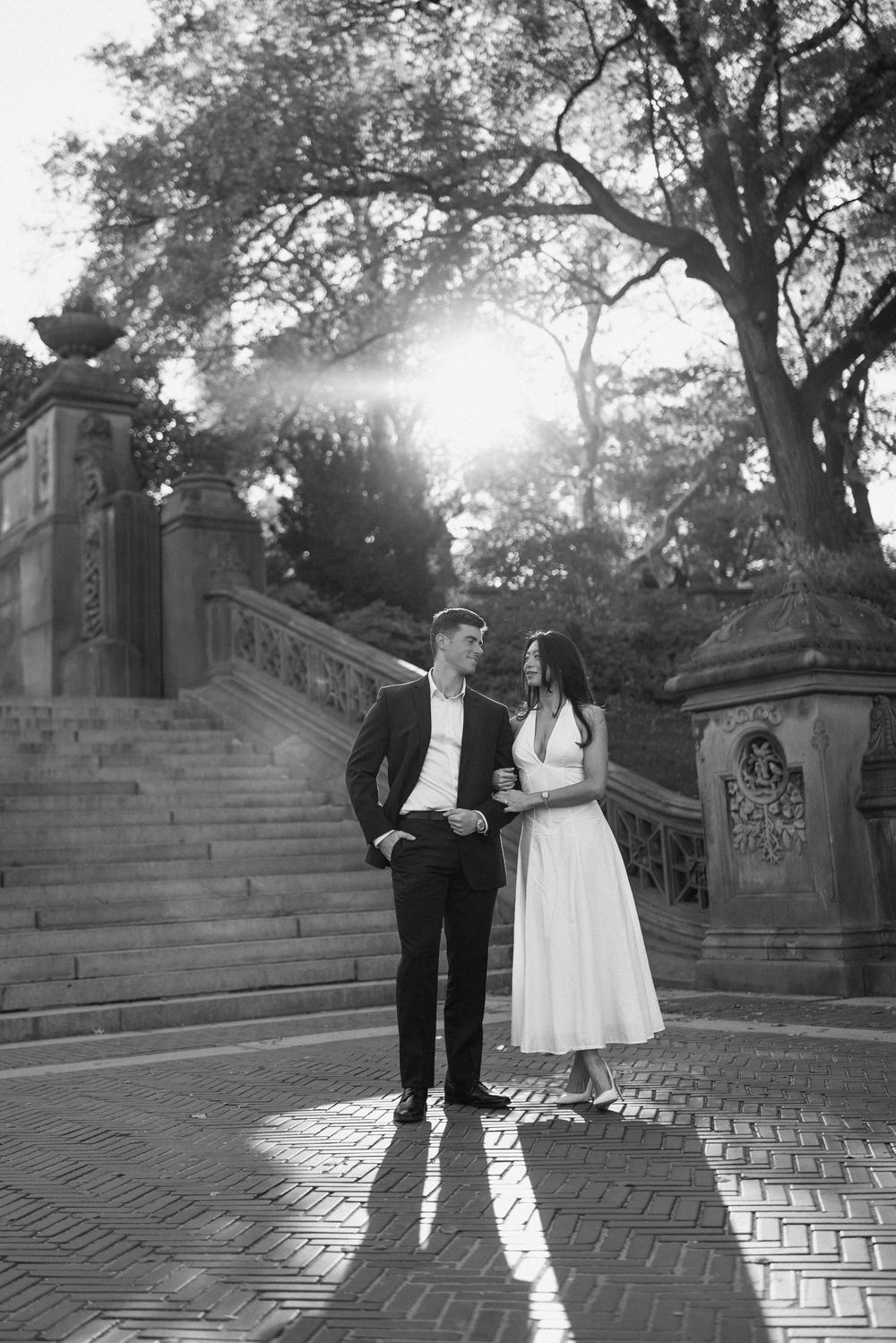 A black and white portrait of a couple dancing on brick steps.
