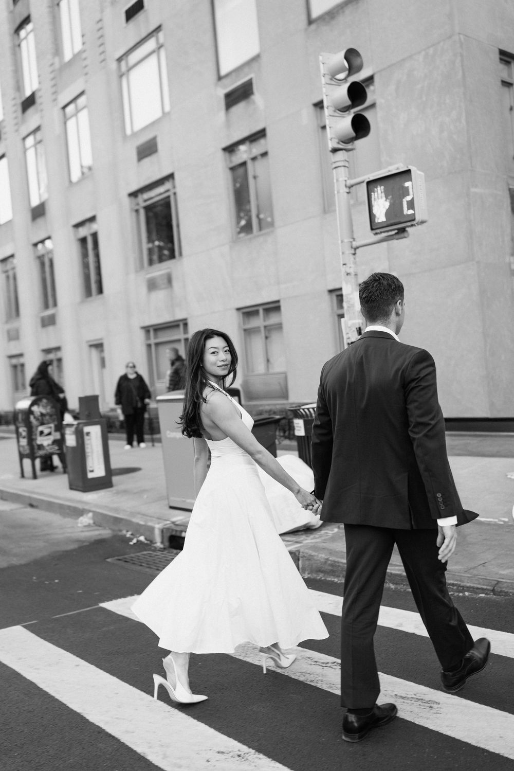 A couple dances playfully on a city crosswalk in black and white.
