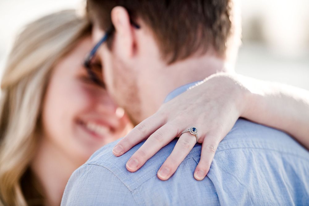 Close up shot of an engagement ring as couple embraces outdoors by Stephanie Coulter Photography