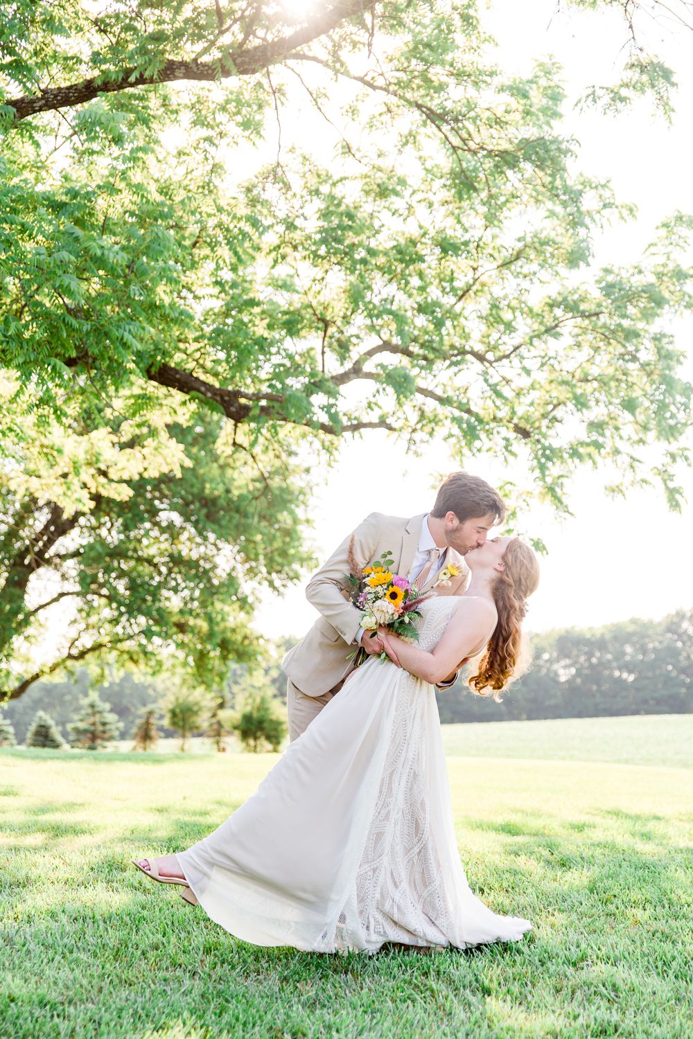 A romantic outdoor wedding portrait under sunlit tree branches with colorful bouquet by Stephanie Coulter Photography