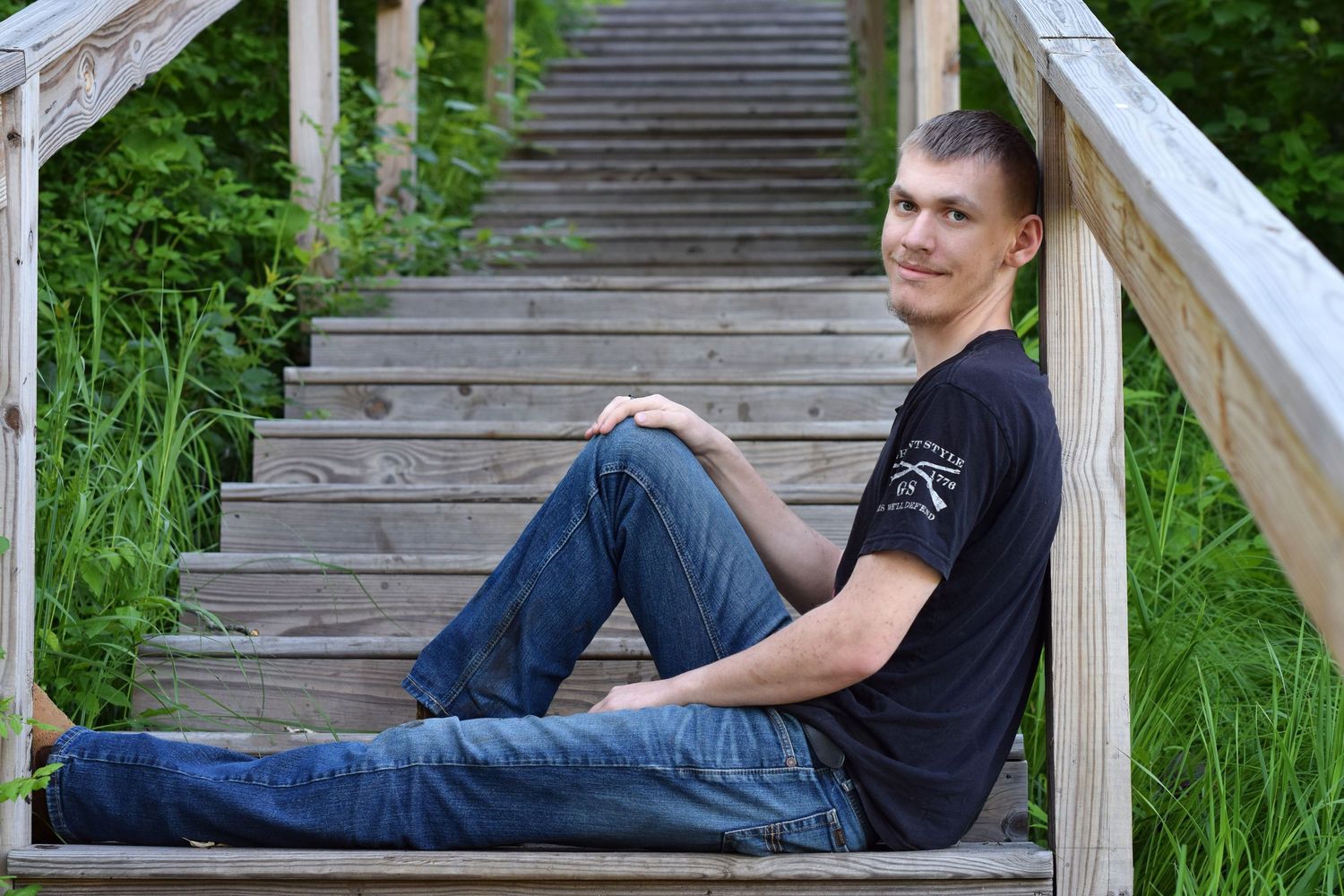 Person in white sweater leans against tree trunk during outdoor portrait session.
