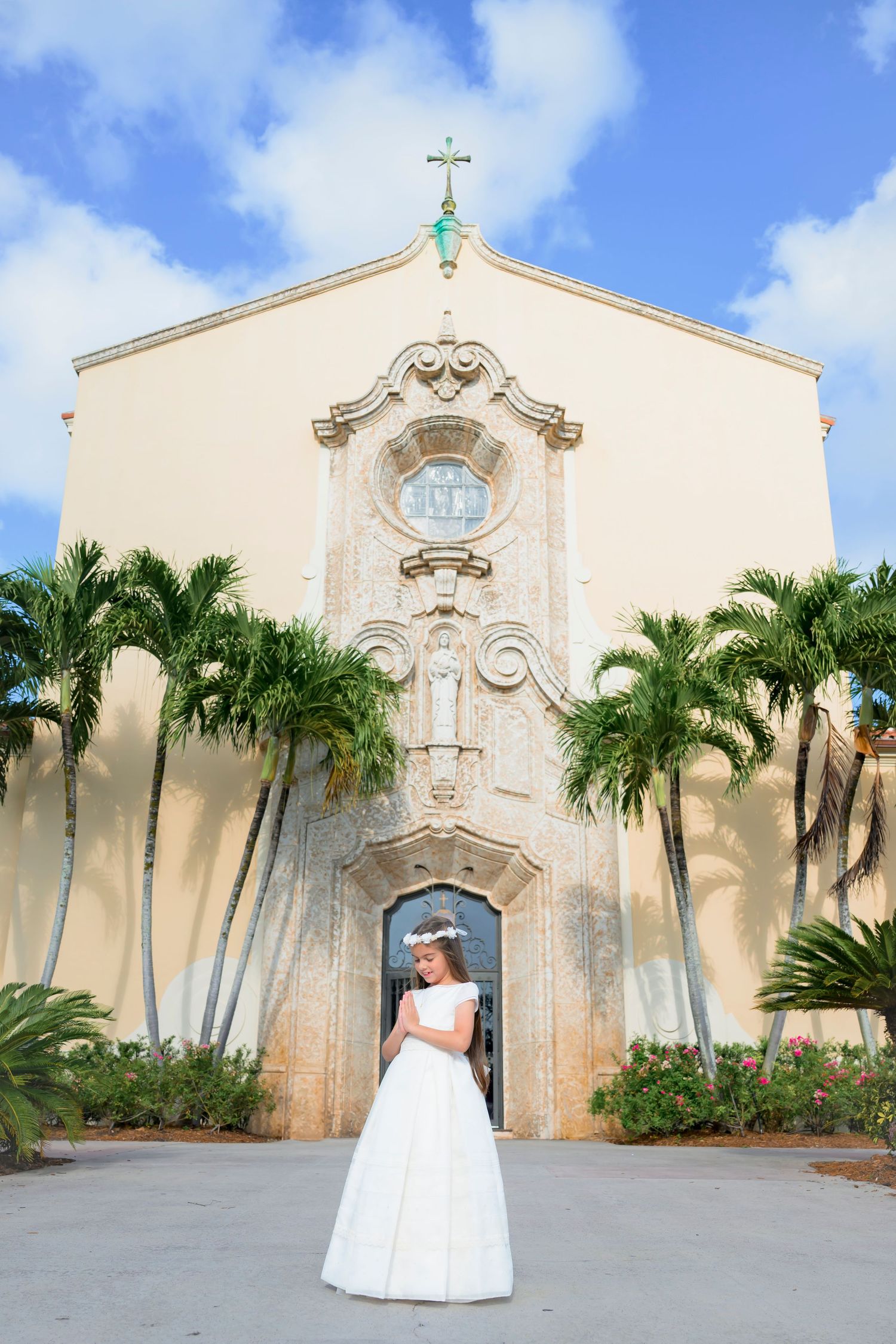 Beautiful Catholic church exterior with ornate facade and tall palm trees framing the cream-colored building entrance.