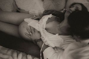 A black and white artistic photograph showing someone resting on a bed in a white lace top.