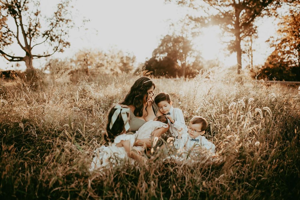 Romantic couple embraces in a golden field during sunset as a photographer captures their intimate moments.