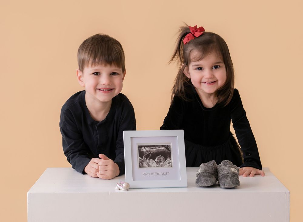 Children laying on the floor in a studio setting with vintage photographs displayed in front of them.