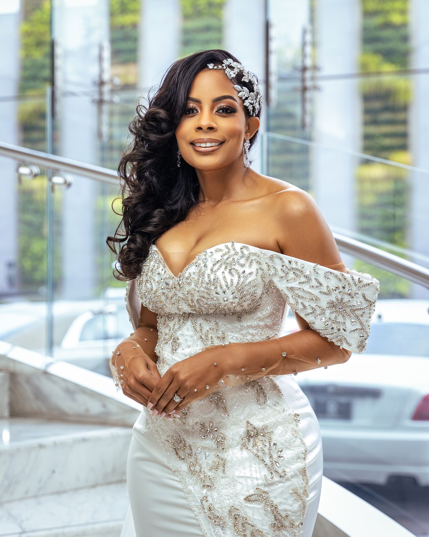 Elegant woman in sparkling white gown and hair accessory smiling wedding photographer.